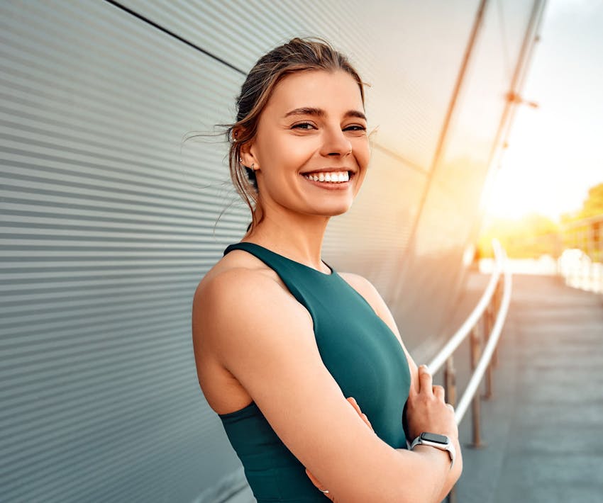 woman outside with her arms crossed leaning against railing