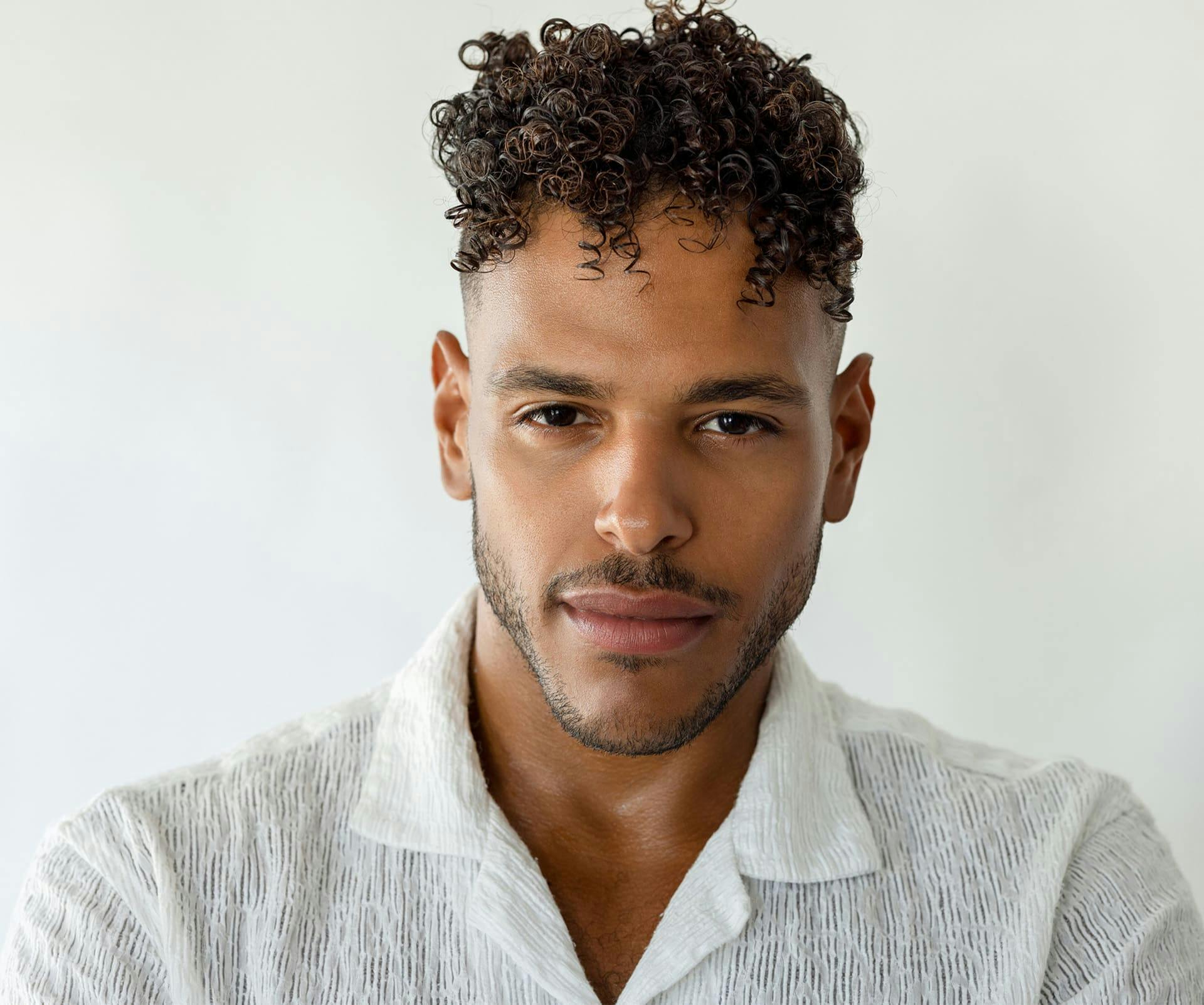 man looking forward with curly hair and a white shirt