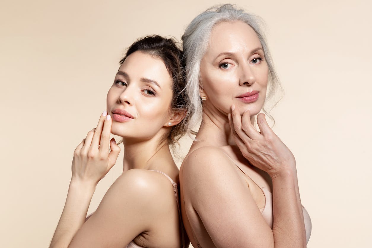 two women leaning on each other with glowy skin and hands