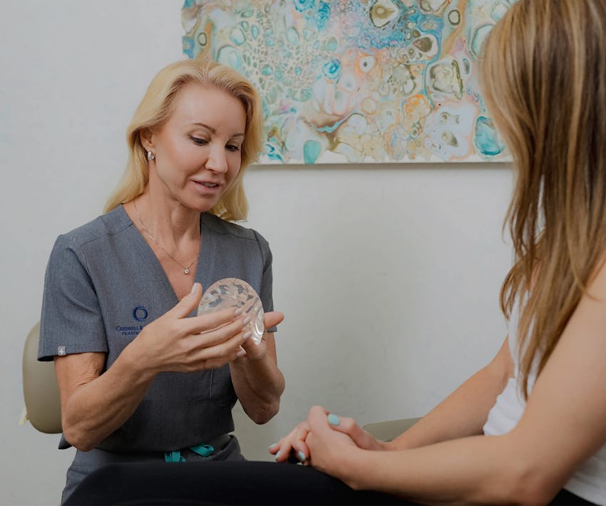 doctor holding breast implant showing patient