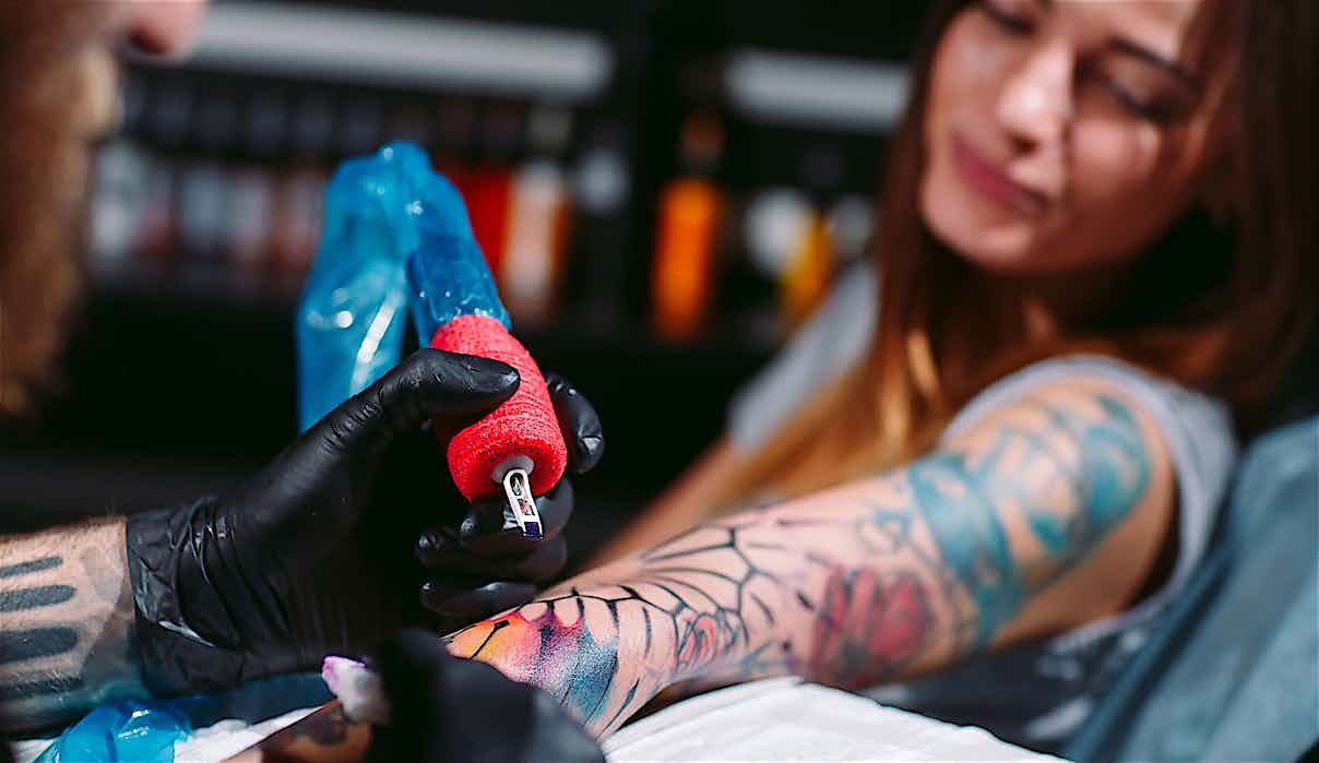 Tätowierer mit Kunden und Tattoomaschine