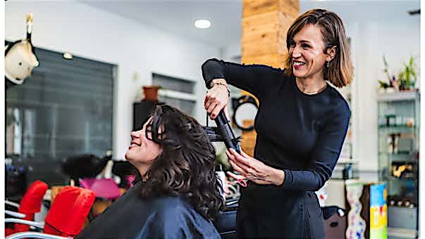 Kassensystem Dienstleistungen - Friseure Friseurin wellt einer Kundin das Haar mit dem
