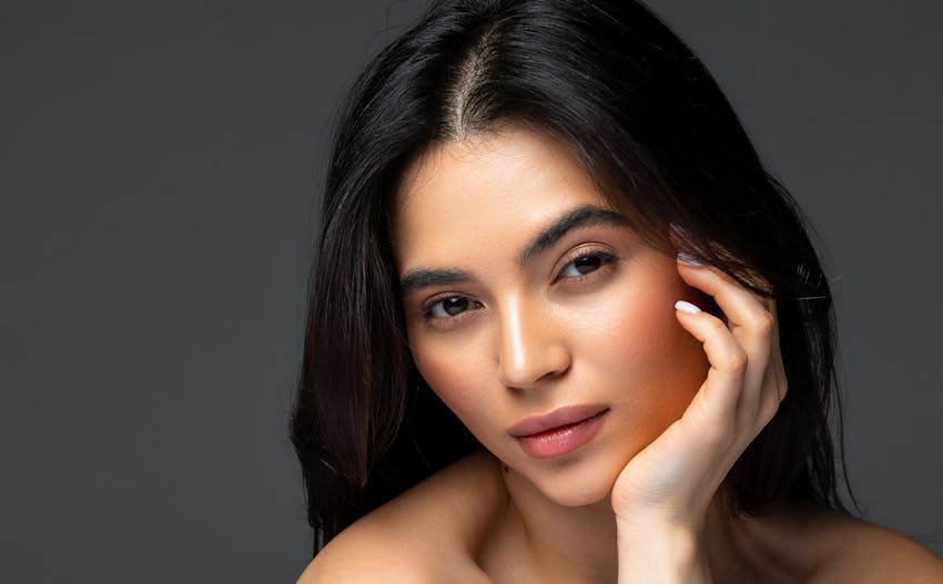 woman looking to the side with hand resting on chin and jaw