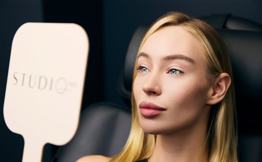 close up of a woman looking at her face in a hand held mirror
