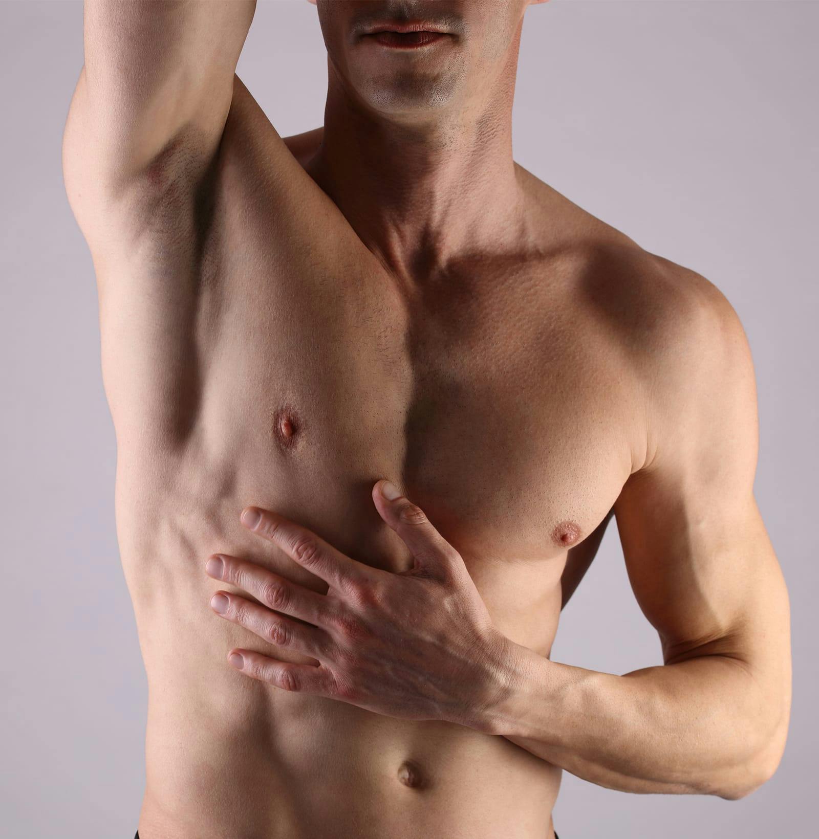 close up of man's torso with hands resting above his head and on his abdomen