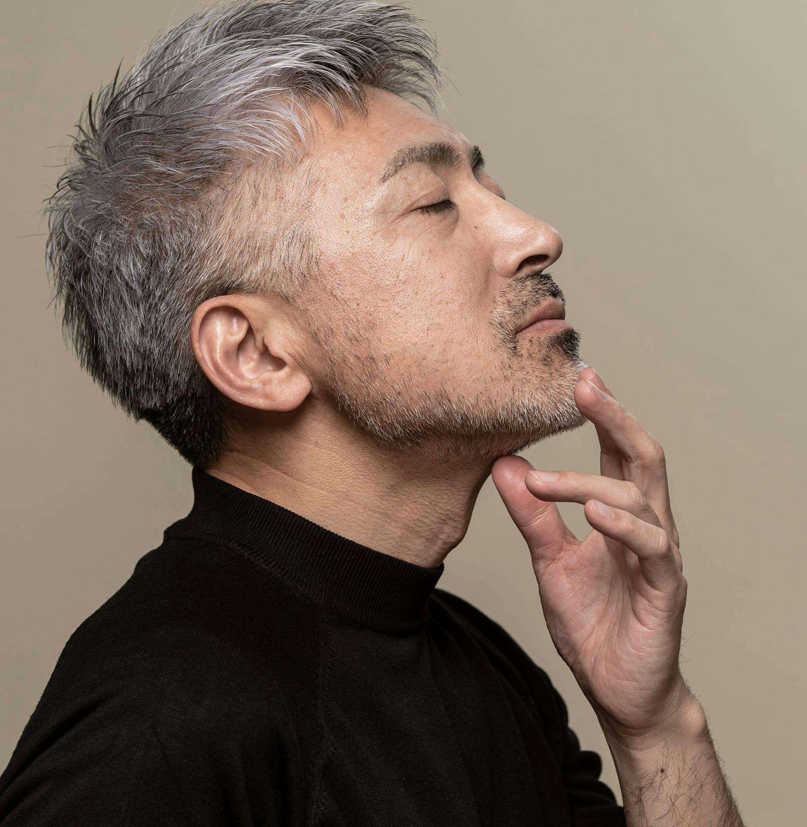 man with head tipped back touching his chin