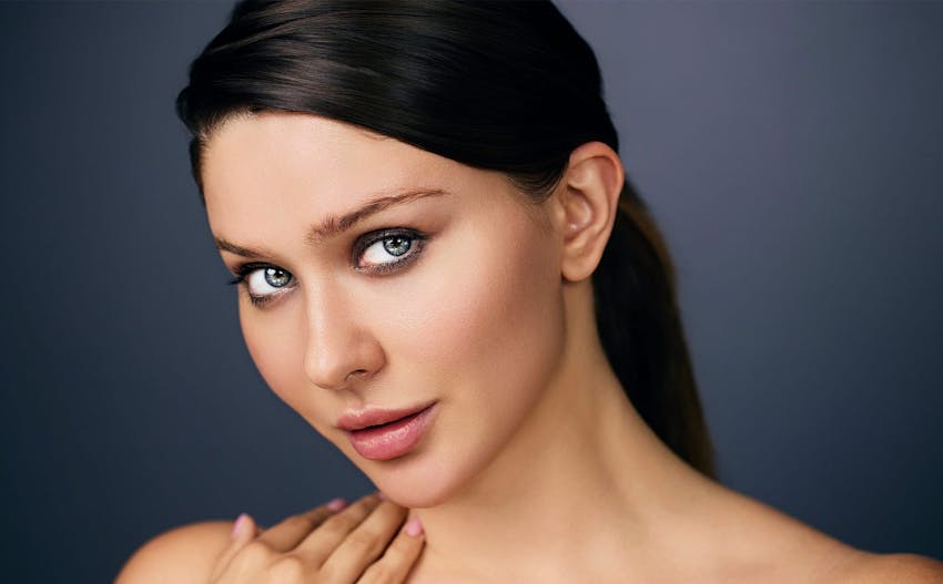 woman touching her shoulder with hair tied back in ponytail