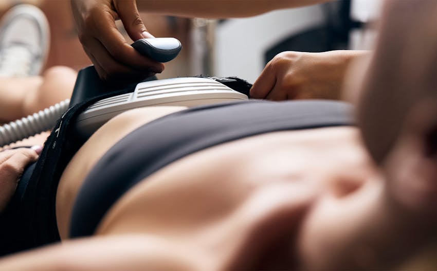 CoolSculpting equipment attached to patients abdomen as they lay on medical table