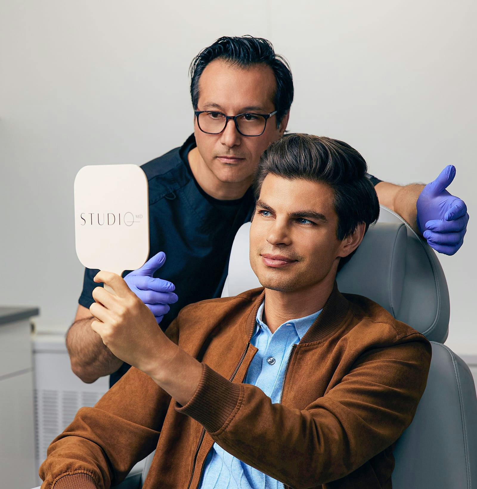 Studio MD provider talking to patient as patient looks in handheld mirror