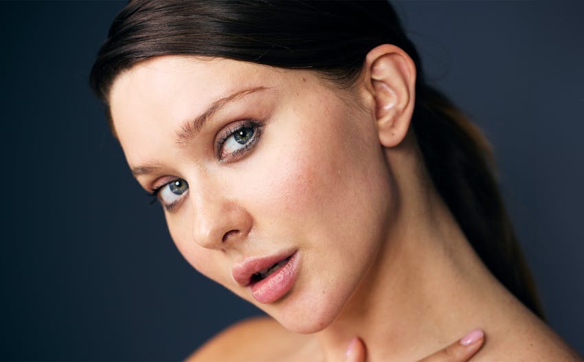 woman touching her neck with hair tied back in ponytail