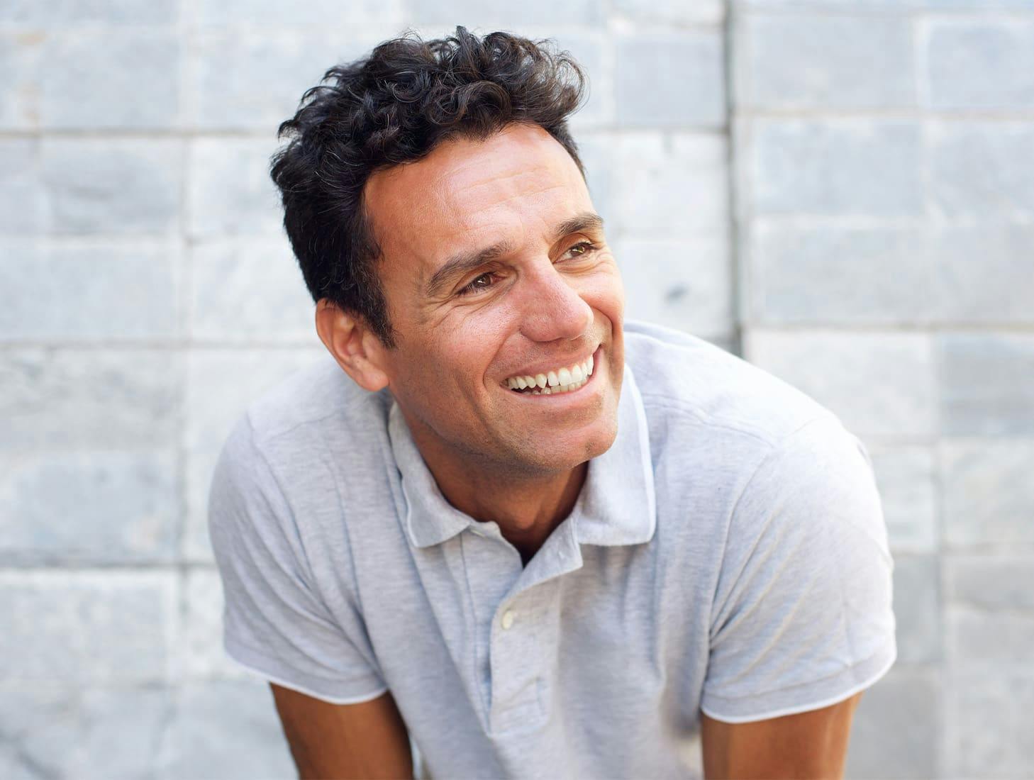 man leaning over and smiling while looking to the right