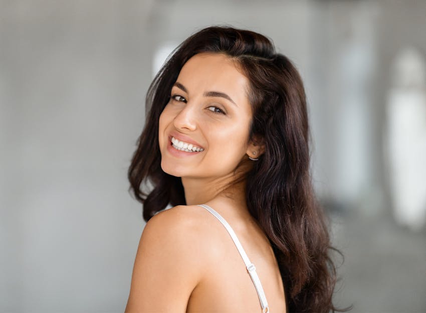 young woman with dark hair looking back over her shoulder