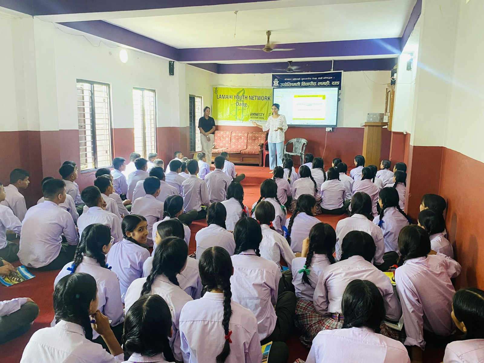 A session in a school hall Students in white uniforms seated in a school hall during a session