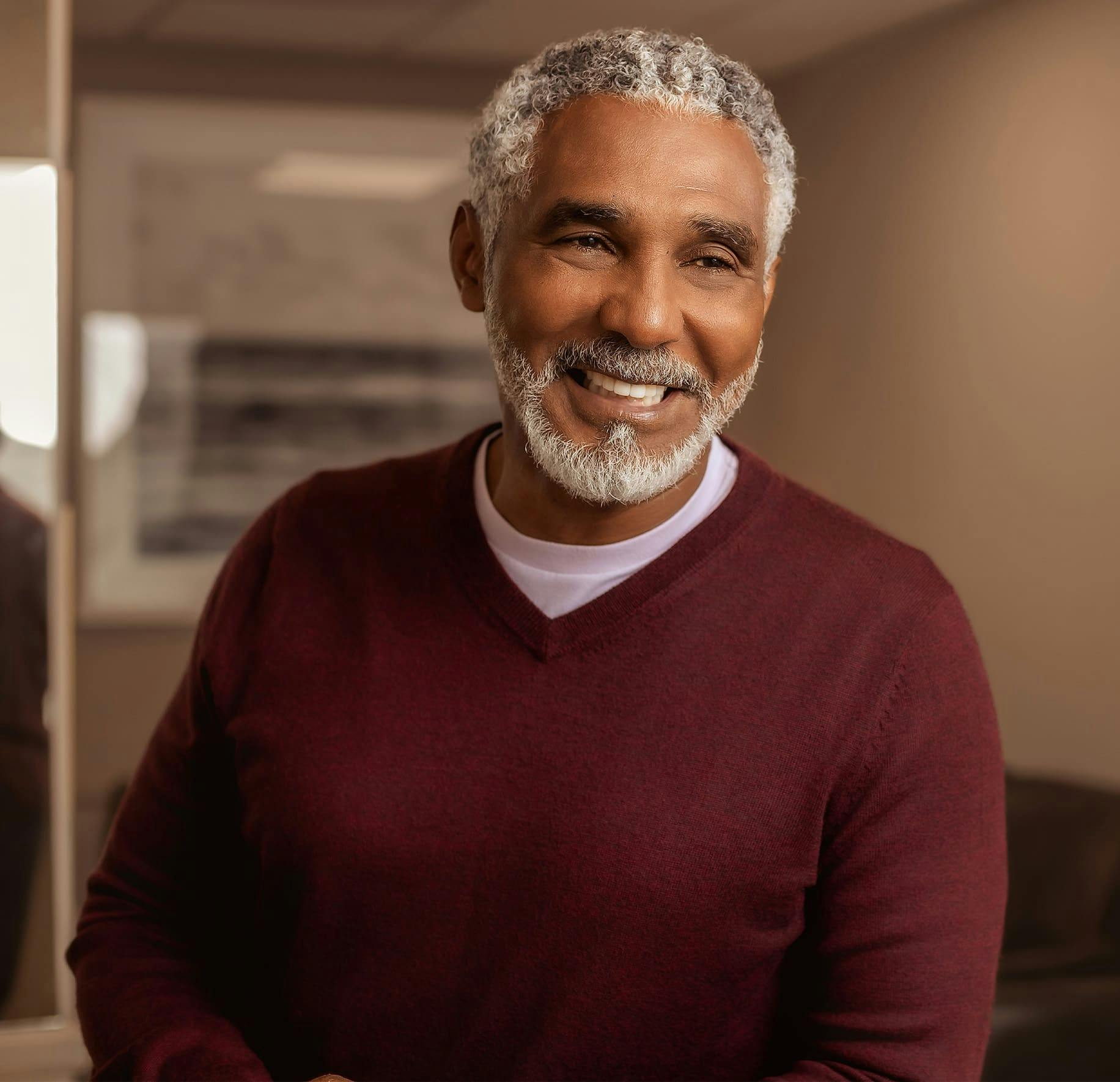 older man smiling in red sweater