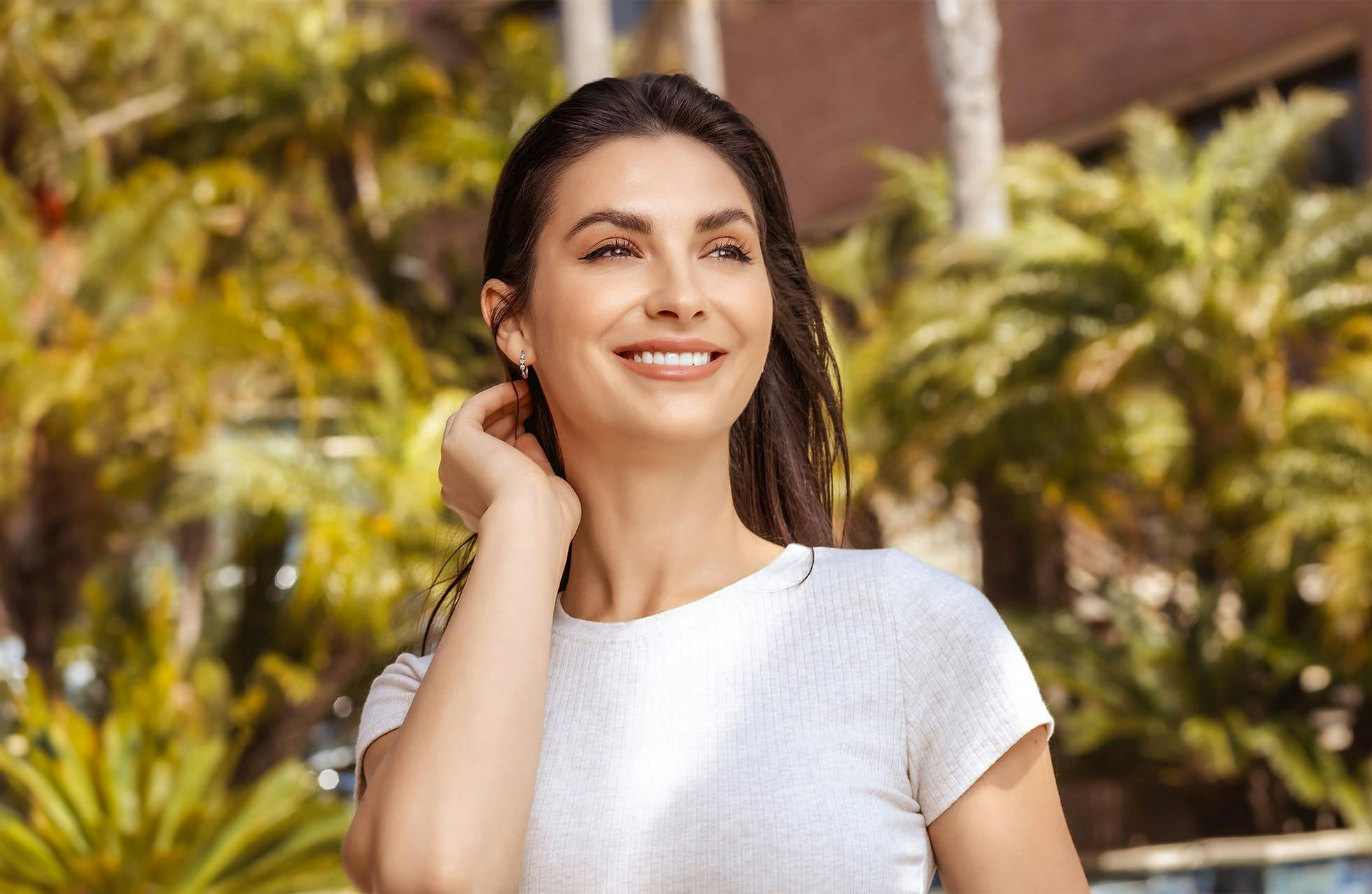 woman outside while tucking her hair behind her ear