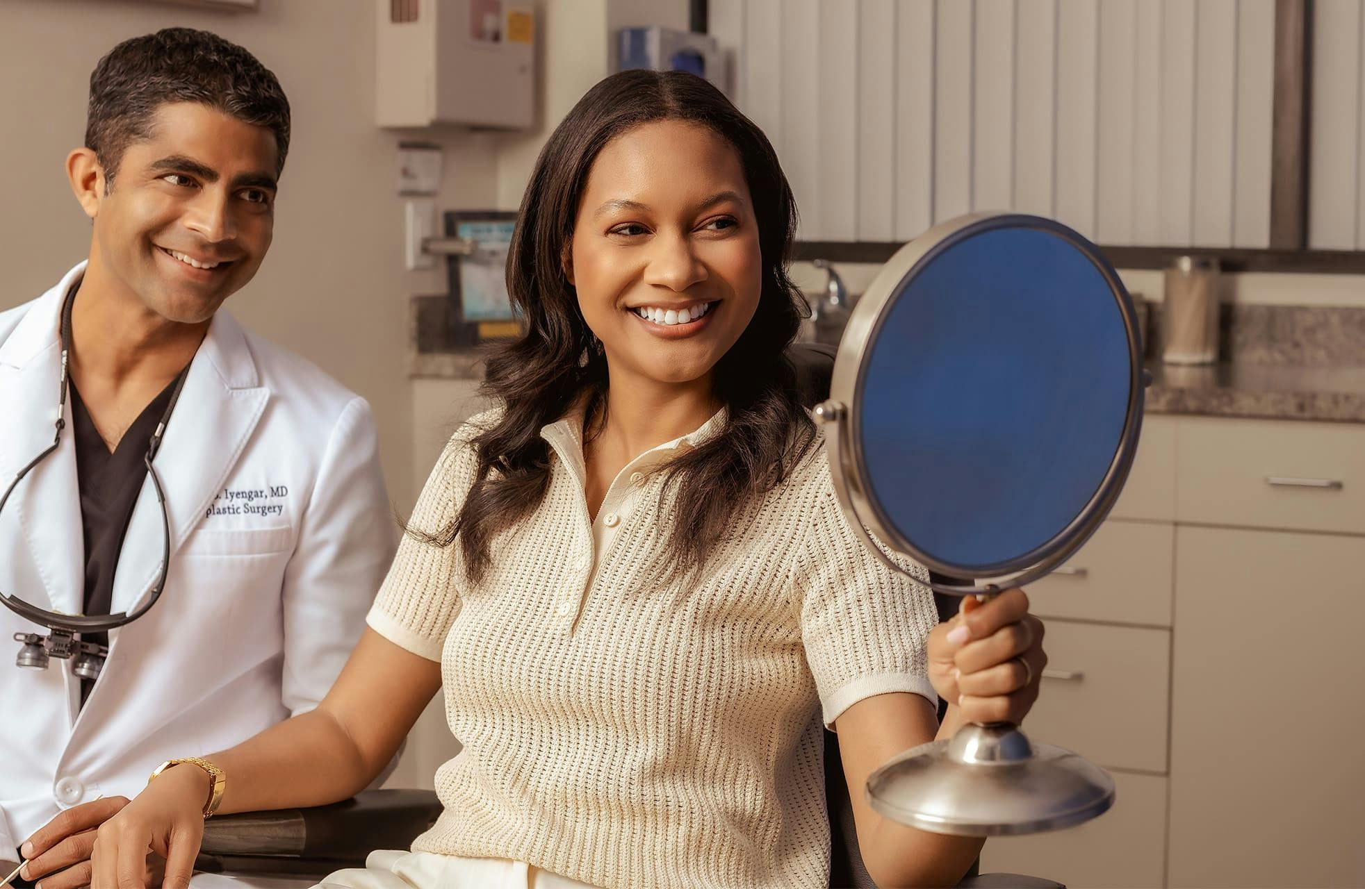patient smiling into mirror with Dr. Iyengar