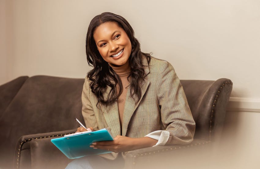 woman smiling while filling out paper work in seat