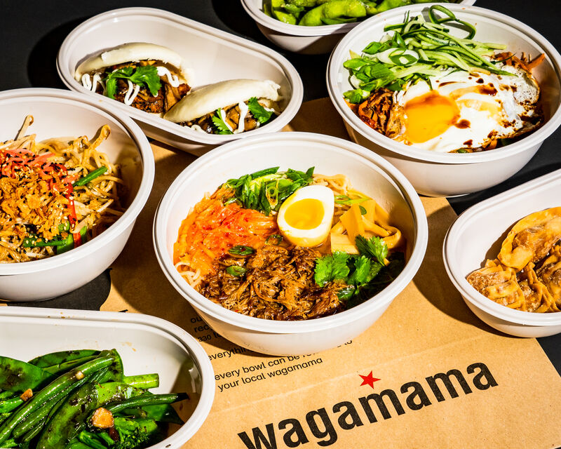 multiple wagamama takeout bowls full of food on table