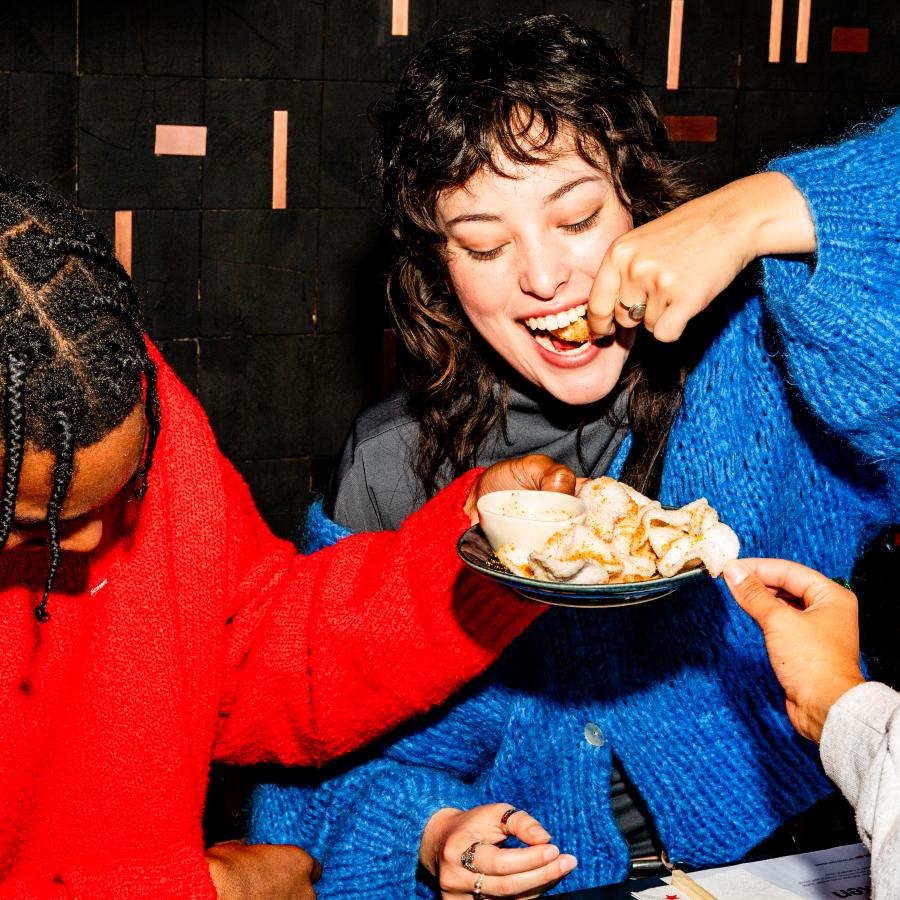 a guy in a red jumper holds a plate of prawn crakers