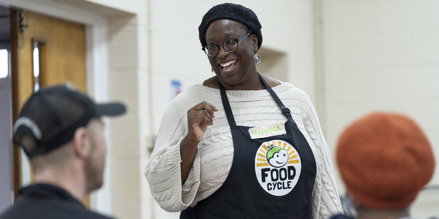 a volunteer at foodcycle laughs whilst interacting with guests