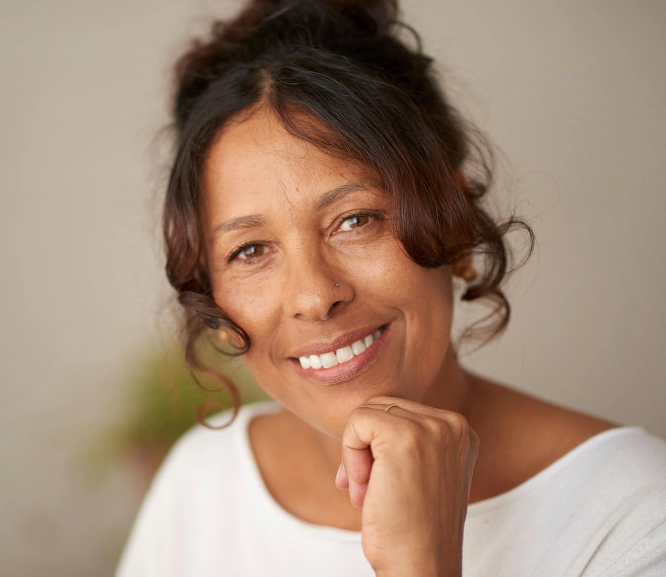 woman with hair tied up and hand under her chin