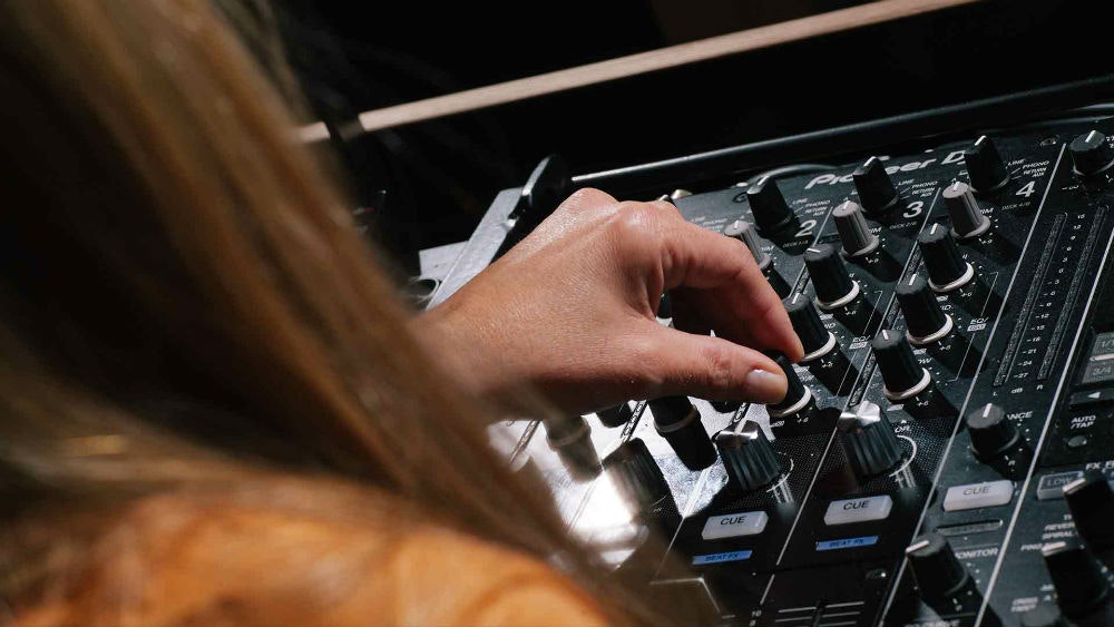 A DJ using a Pioneer DJM 900 NXS2 DJ set up for beginners in a Pirate Studios DJ room