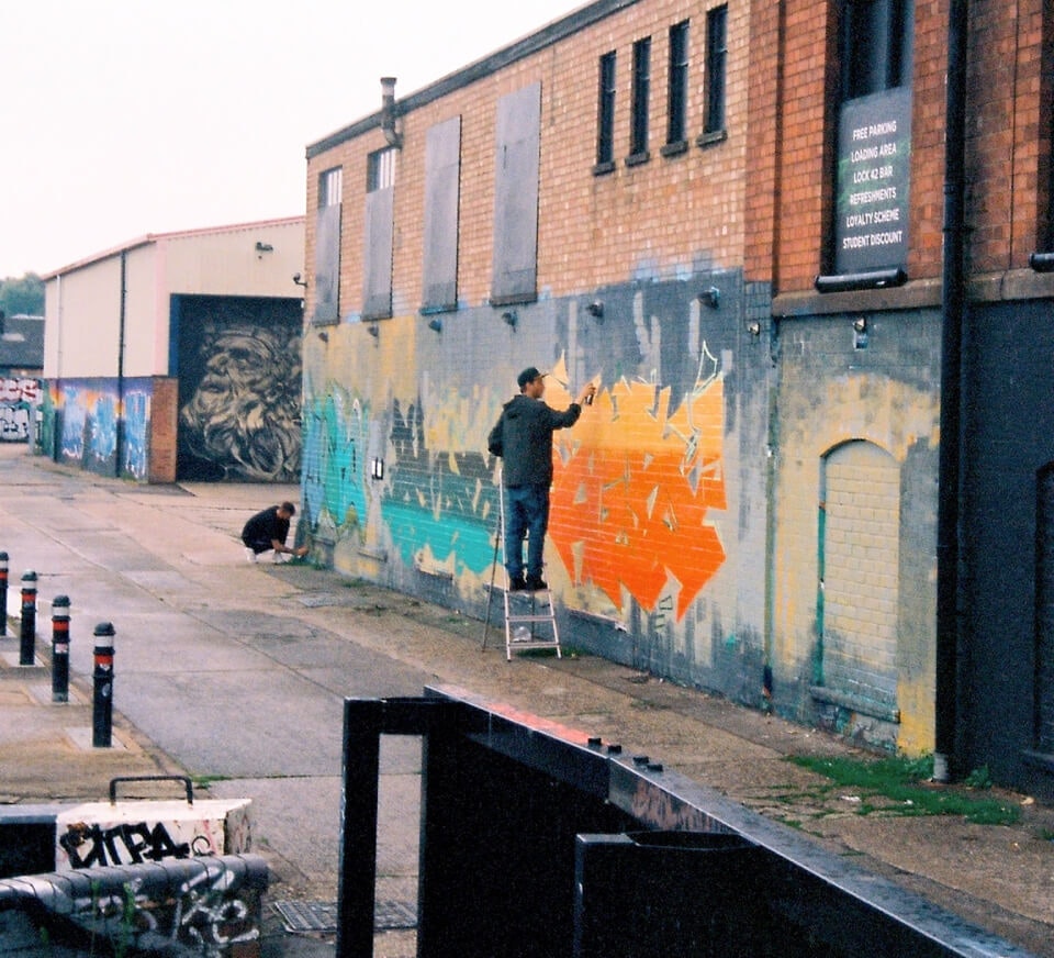 Graffiti artist painting a residential wall close to Pirate Studios Leicester