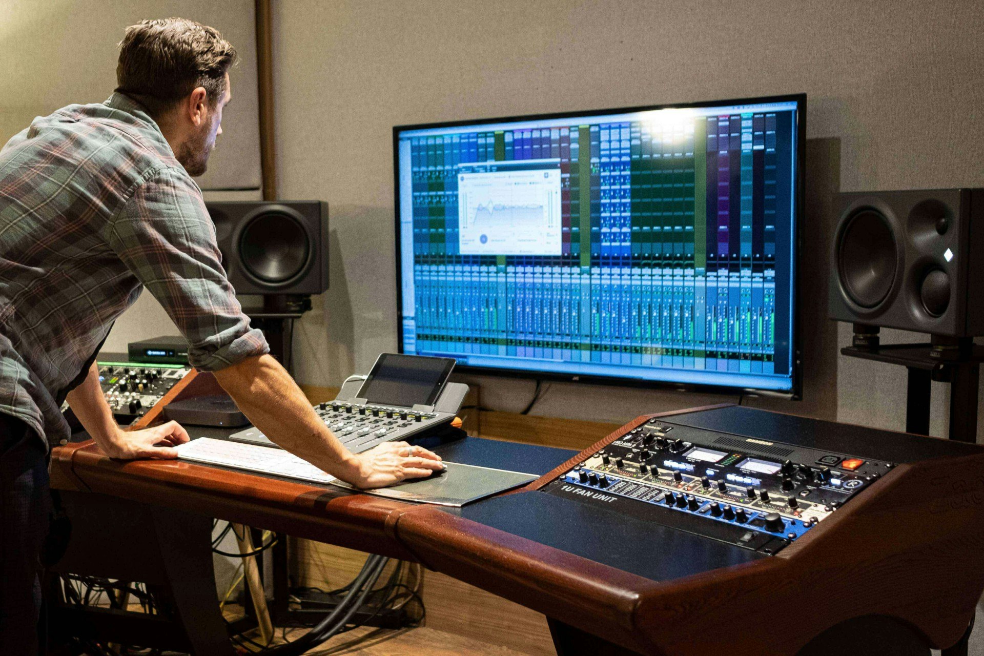 An inside shot of an LA recording studio  with active monitors, large display screen, and more