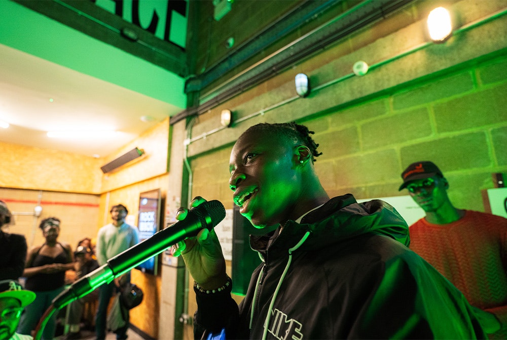 This image may contain: electrical device, microphone, person, lighting, urban, face, head, karaoke, leisure activities