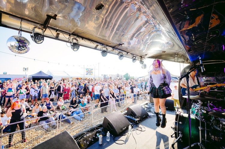 This image may contain: concert, crowd, person, urban, female, girl, teen, clothing, skirt, microphone