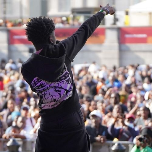 This image may contain: person, solo performance, clothing, glove, crowd, face, happy, head, people, hat