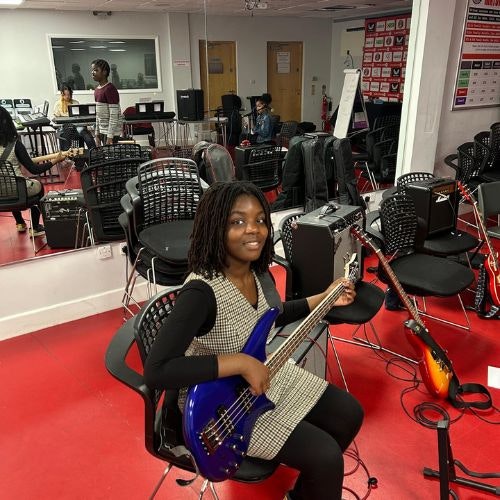 This image may contain: person, adult, female, woman, guitar, musical instrument, guitarist, musician, speaker, shoe