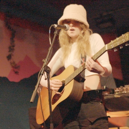 This image may contain: guitar, adult, female, person, woman, concert, guitarist, microphone, solo performance, face