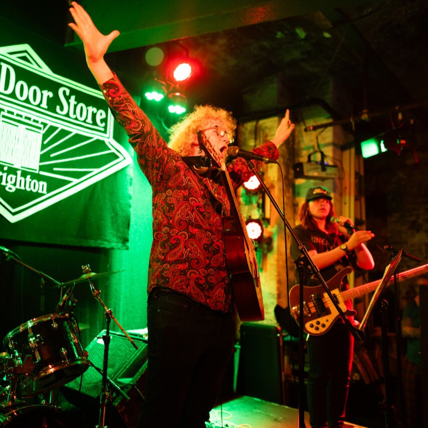 This image may contain: concert, crowd, person, lighting, microphone, hat, guitar, rock concert, urban, group performance