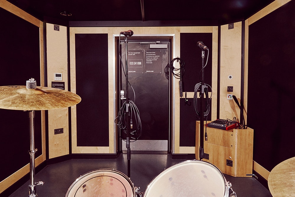 This image may contain: electrical device, microphone, indoors, drum, musical instrument, percussion, interior design, desk, furniture, table