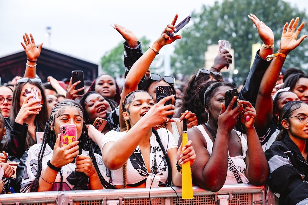 This image may contain: celebrating, person, mobile phone, bracelet, adult, female, woman, glasses, cup, face