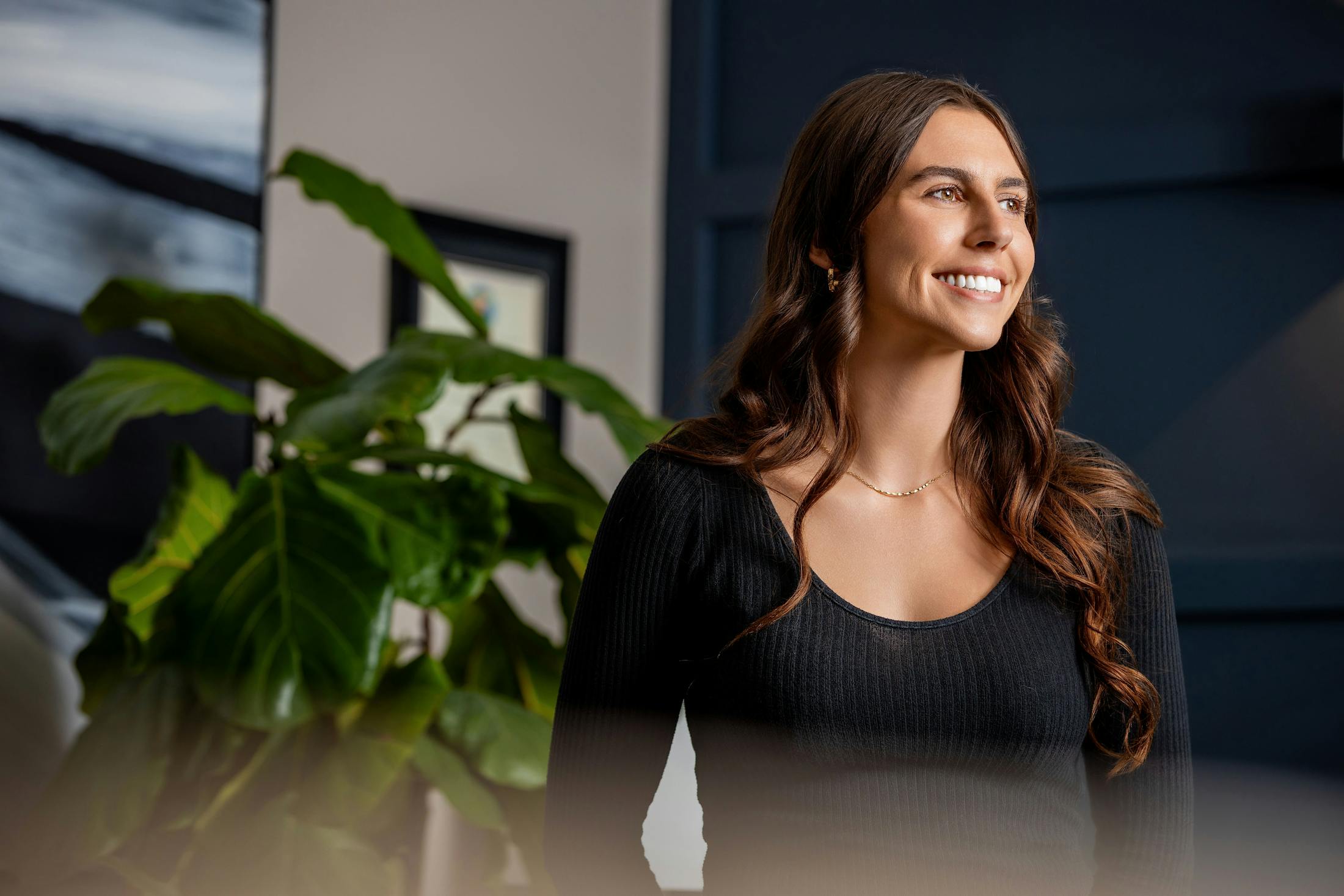 woman smiling with plant next to her