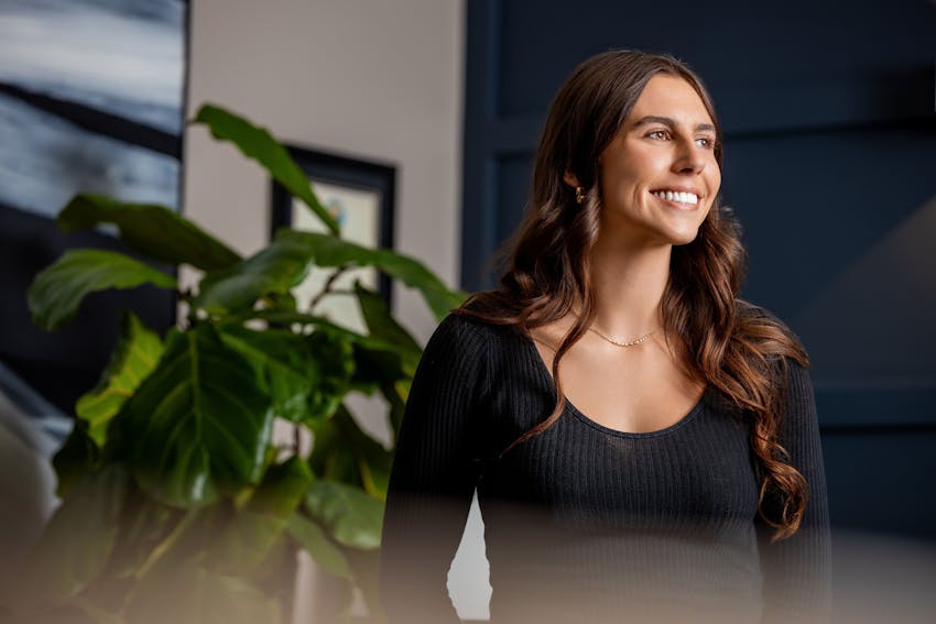 woman smiling with plant next to her
