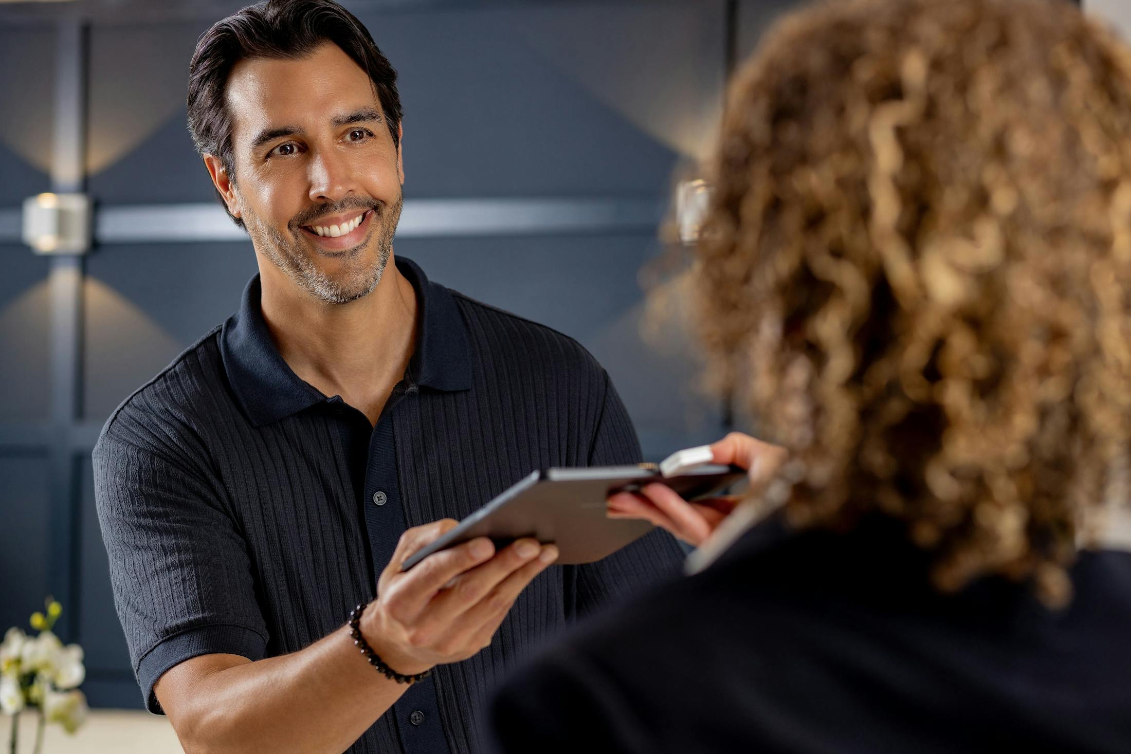 man smiling while getting handed an ipad