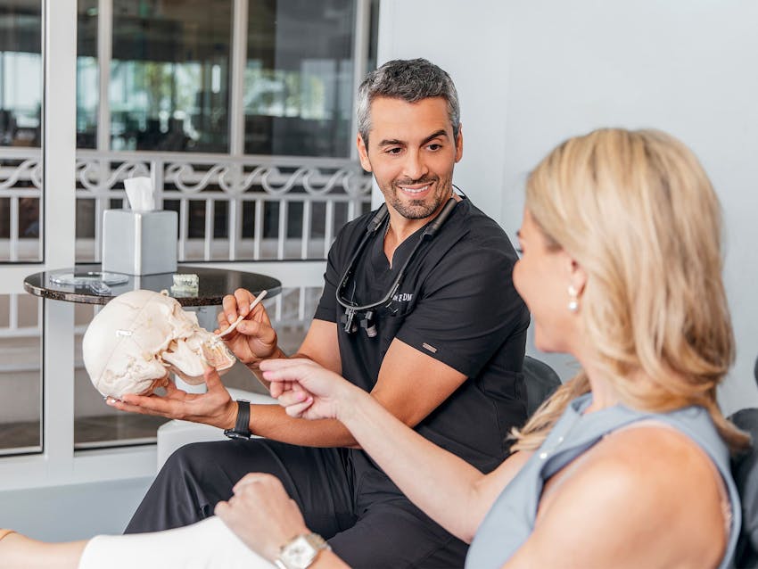 staff member pointing to the teeth on fake skull to patient