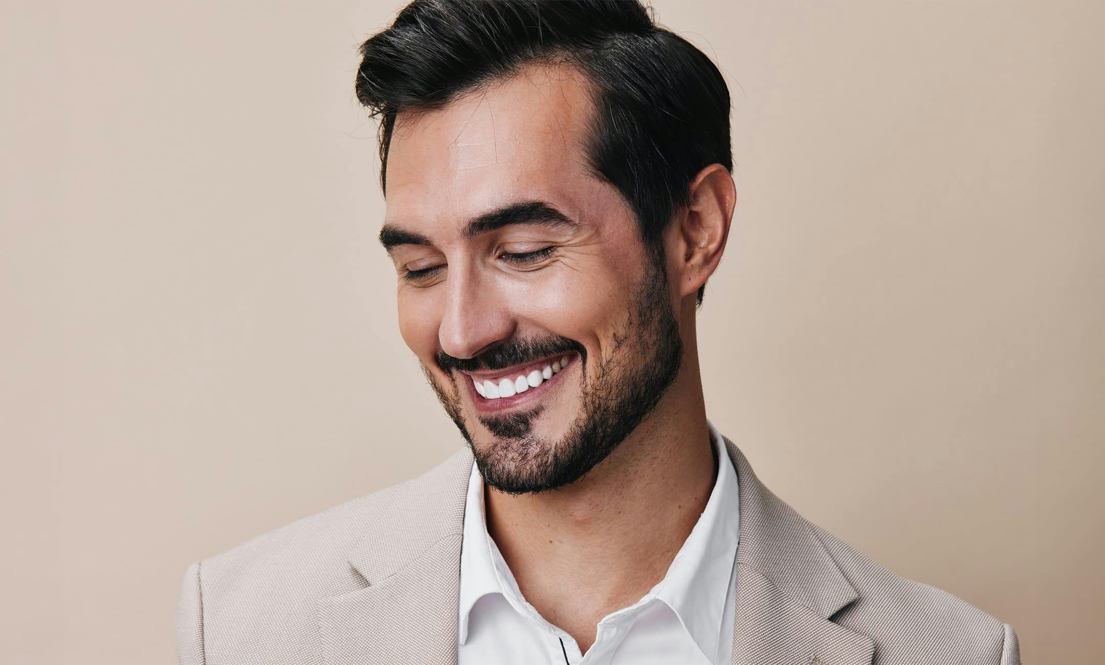 man smiling in suit and looking downwards