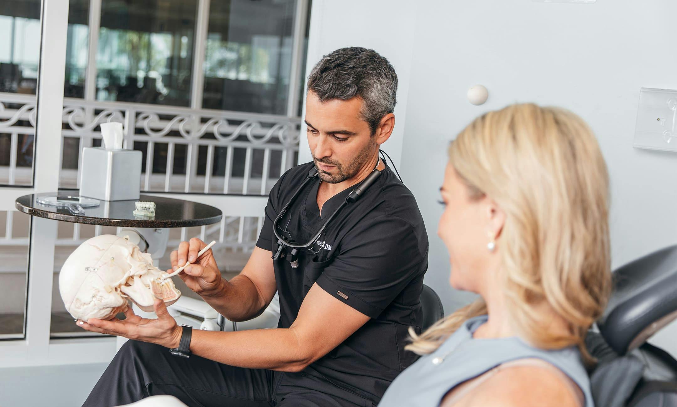 staff member holding a fake skull and showing patient the mouth of it