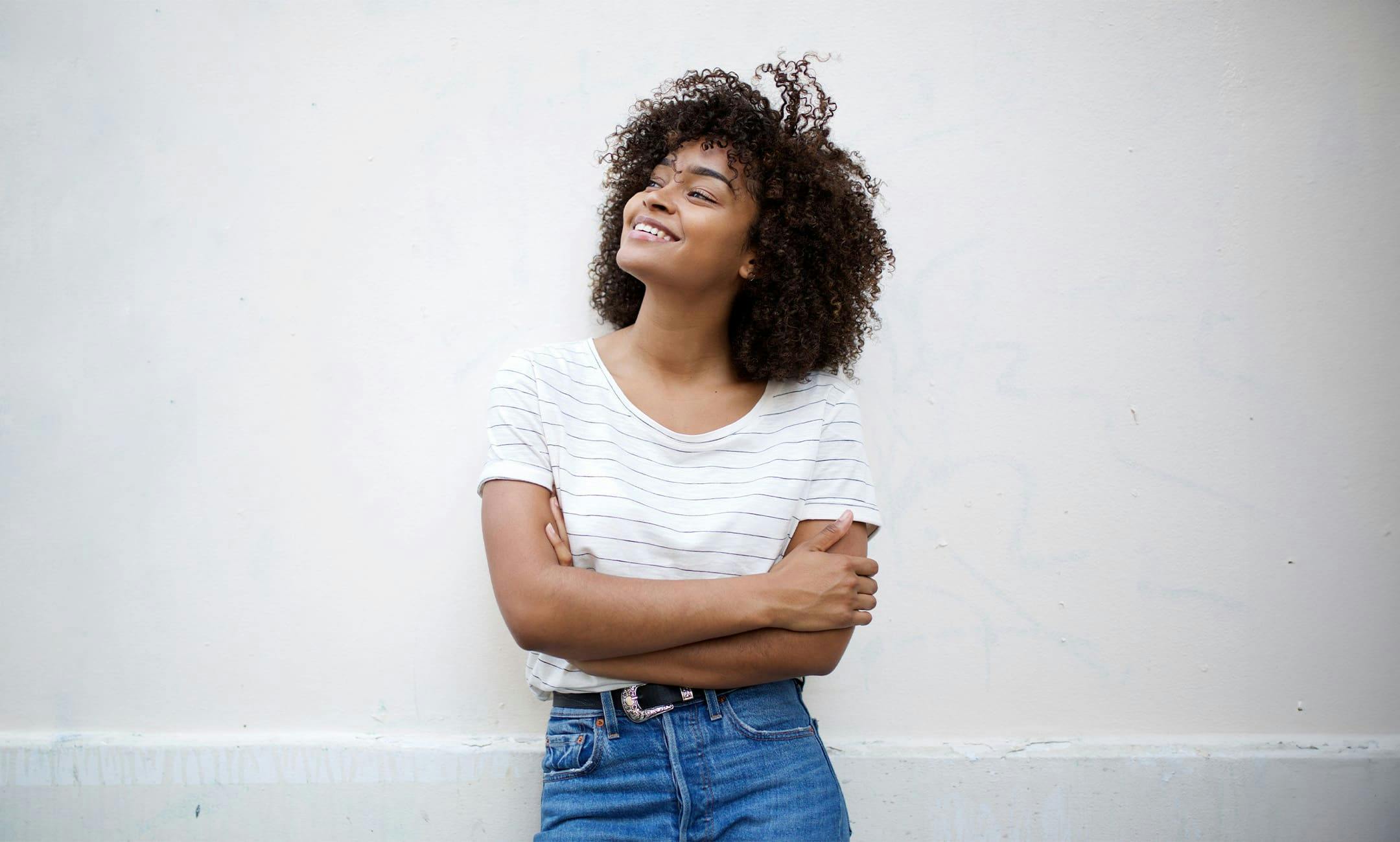 woman leaning against wall with her arms crossed