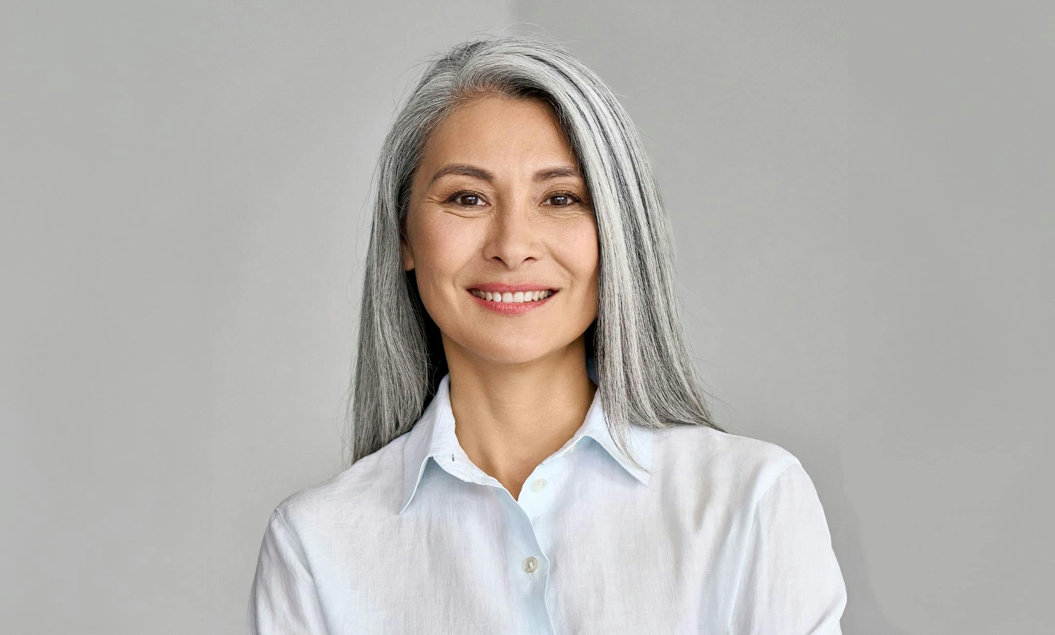 older woman smiling forward in white shirt