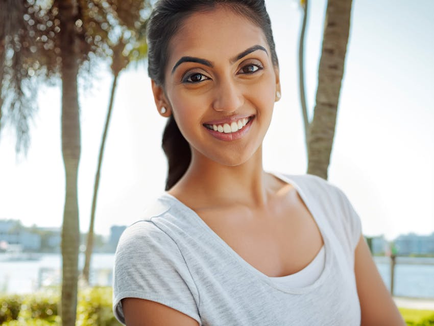 woman smiling forward with hair tied into a ponytail