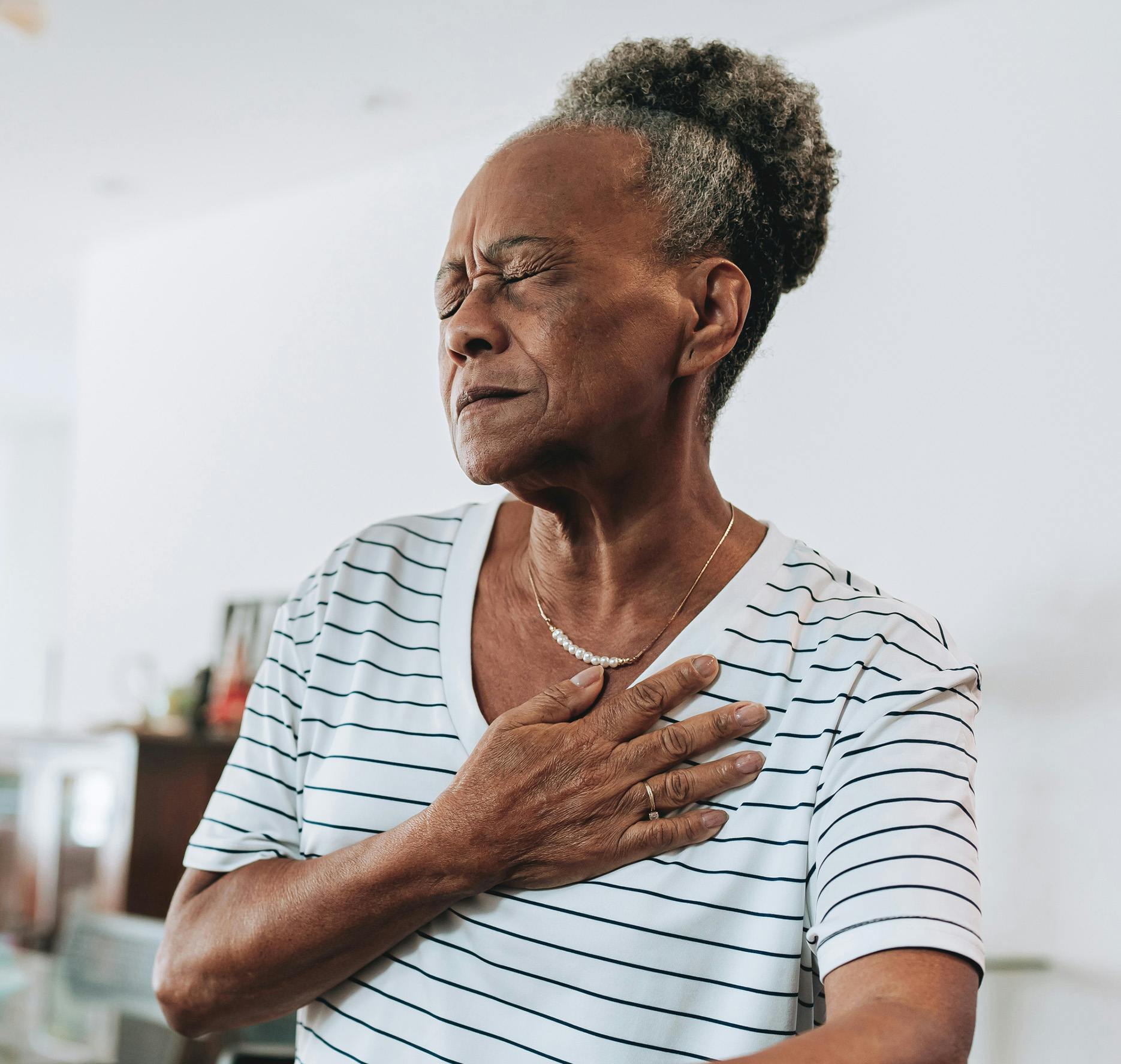 elderly woman with hand on chest