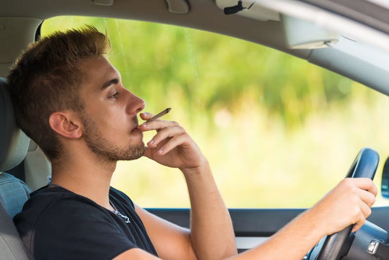 guy driving while smoking weed
