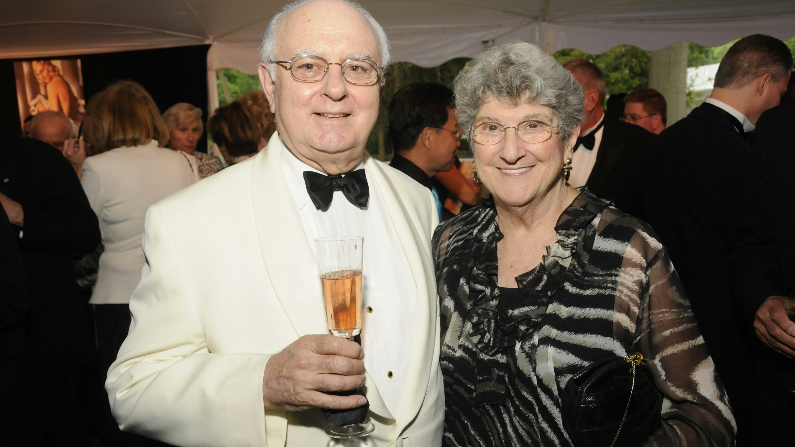 Ed and Elaine Schroeder standing side by side, Ed is holding a champagne flute at a Caramoor Opening Night Gala c. June 2010