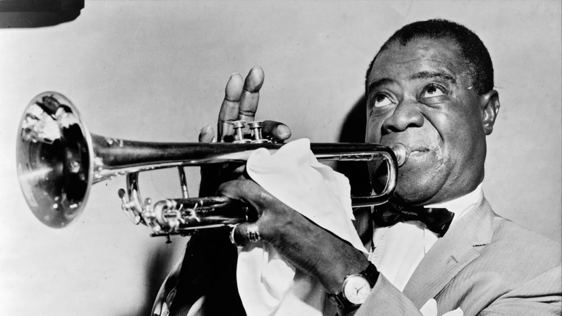 An archival photo of Louis Armstrong playing the trumpet.