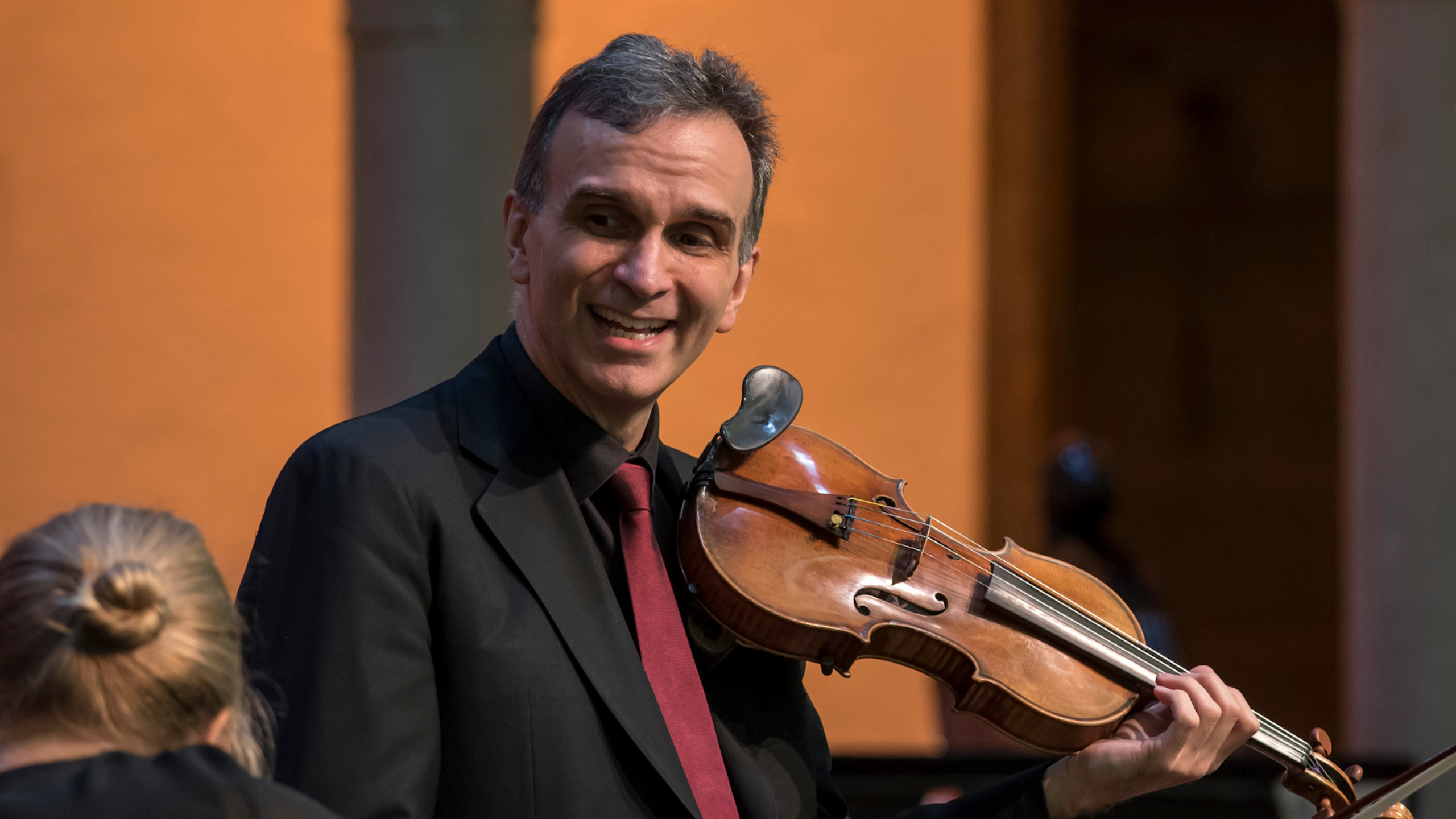 Gil Shaham smiles on stage of the Venetian Theater holding his violin.